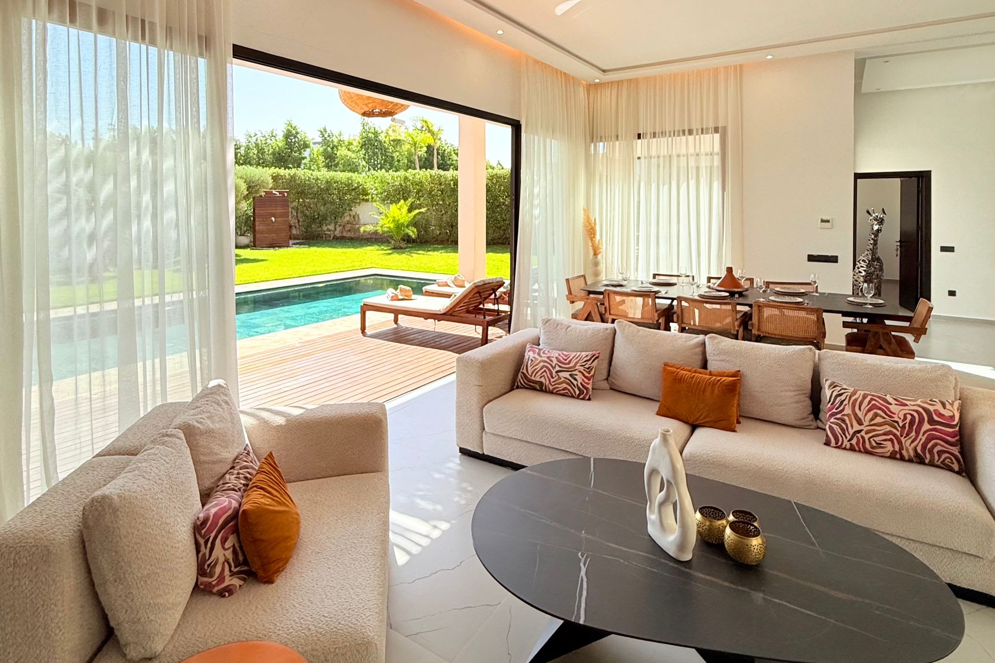 Salon lumineux d’une villa moderne au Maroc avec vue sur la piscine et le jardin.